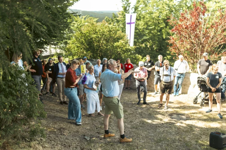 Person spricht vor einer Besuchergruppe im Garten während der Bewertung des Dorfwettbewerbs