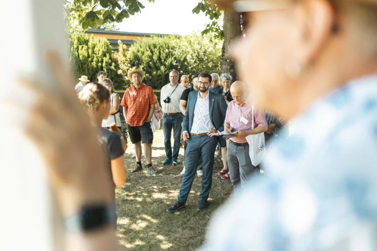 Gruppe bei einer Begehung im Freien, im Vordergrund zuhörende Personen