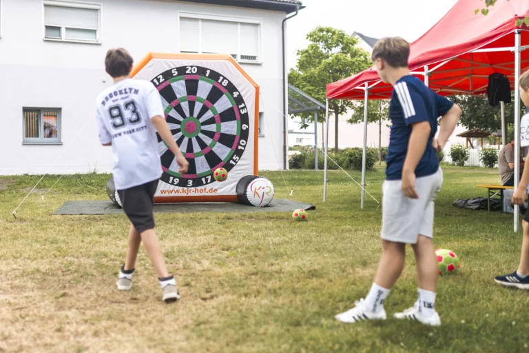 Jungen spielen Fußballdart auf der Wiese bei Zelten des Weltkindertags