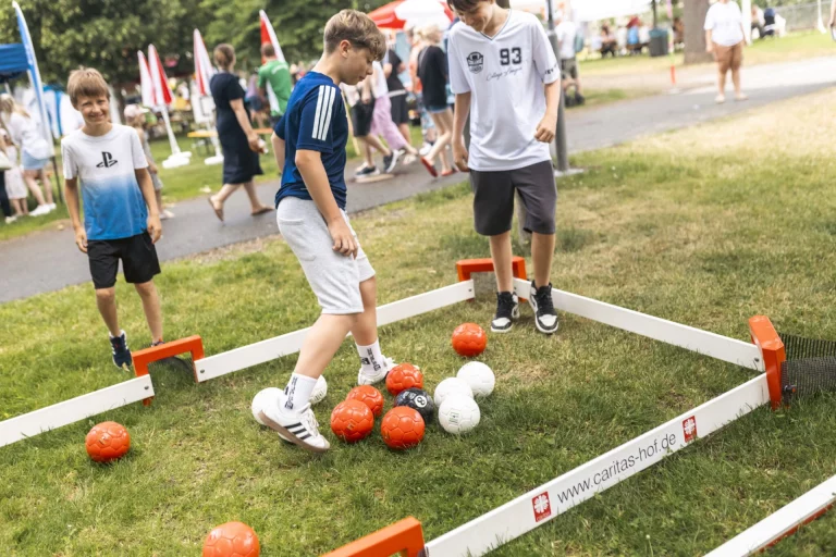 Jugendliche spielen an einem Soccer-Court mit Baellen im Park