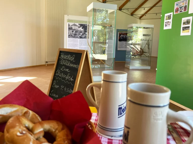 Brezelkorb und Bierkrüge im Vordergrund, dahinter Ausstellungsvitrinen und Tafel zum Wiesenfest