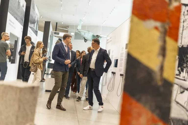 Besuchergruppe in der Ausstellung des Grenzmuseums Mödlareuth, im Vordergrund ein farbiges Grenzzaun-Fragment