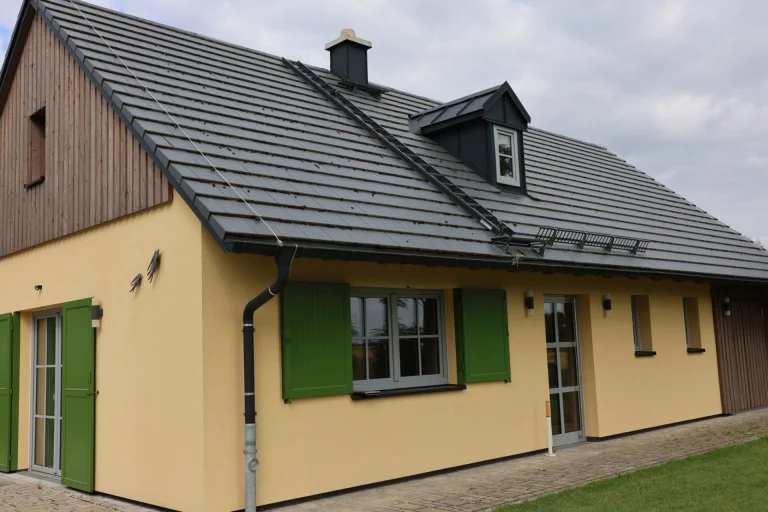 Einfamilienhaus mit gelber Fassade, grünen Fensterläden und Dachgaube