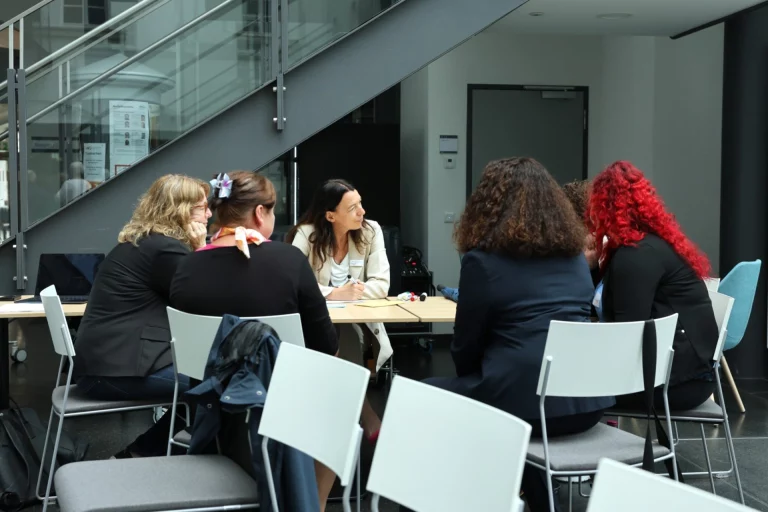 Gruppe von Frauen im Gespräch an einem Tisch im Foyer