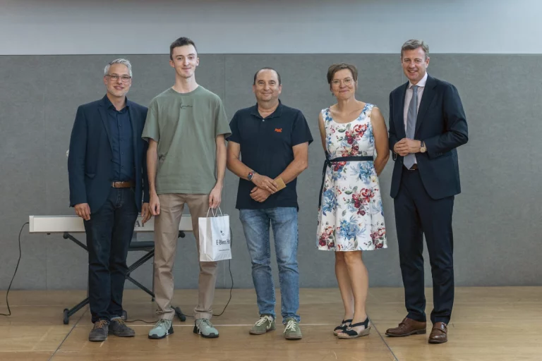 Fünf Personen stehen nebeneinander bei der Preisverleihung, eine Person hält eine Geschenktüte