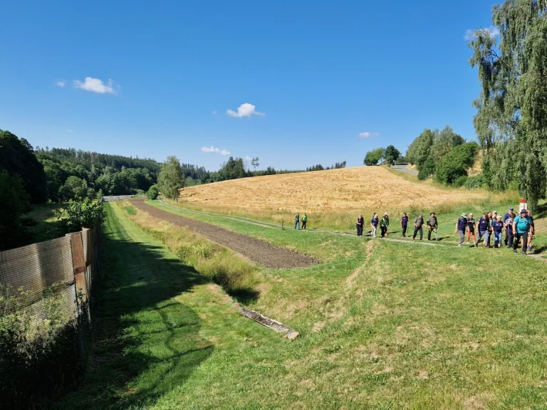 Wandergruppe auf einem Feldweg zwischen Wiesen bei Mödlareuth
