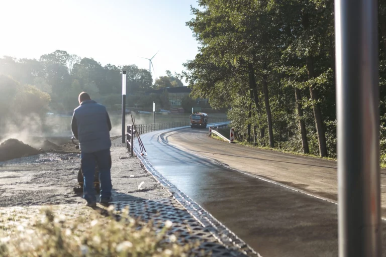 Mann mit Kehrmaschine reinigt neuen Gehweg entlang der Straße bei Mödlareuth