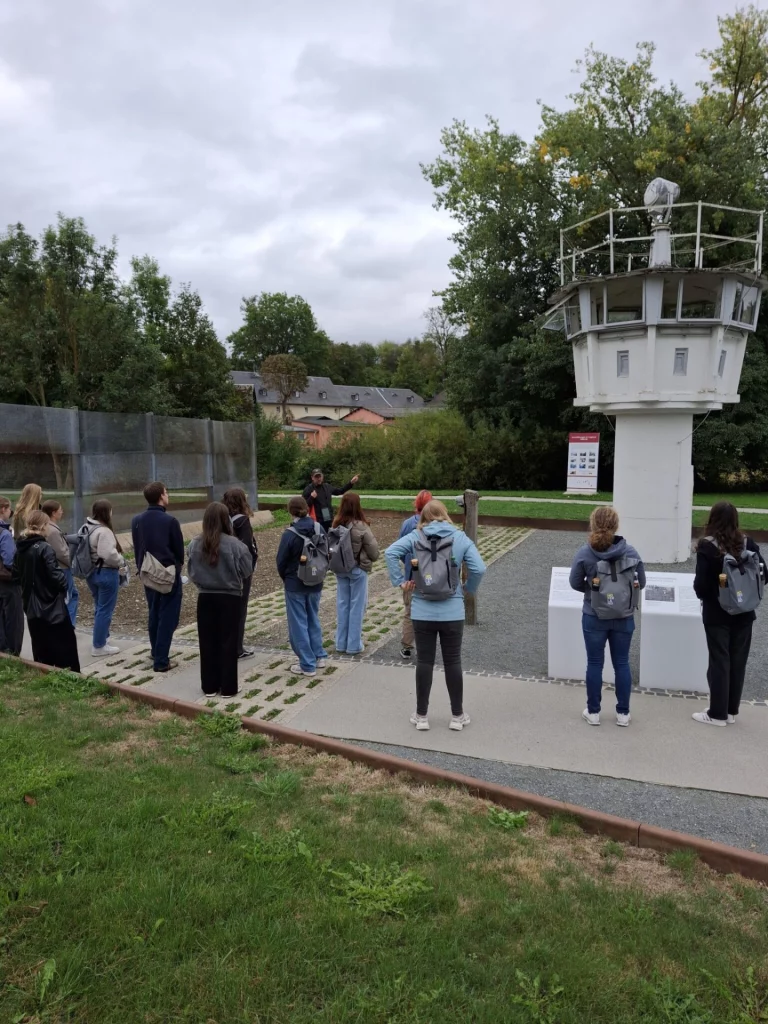 Gruppe von Jugendlichen mit Rucksäcken vor einem ehemaligen Grenzwachturm bei einer Führung